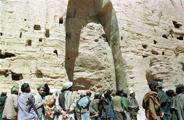 FILE - In this March 26, 2001 file photo, Taliban soldiers stand at the base of the mountain alcove where the world's tallest Buddha statue once stood up to 180 feet high, in Bamiyan, Afghanistan. German scientists say it is possible to reconstruct at least one of the giant 1,500 year-old Buddha statues in central Afghanistan that had been dynamited by the Taliban ten years ago despite a worldwide outcry. Erwin Emmerling of Munich's Technical University said Monday, Feb. 28, 2011, his researchers studied several hundred fragments of the statues that once towered up to 180 feet high in Bamiyan province.  (AP Photo/Amir Shah, File)